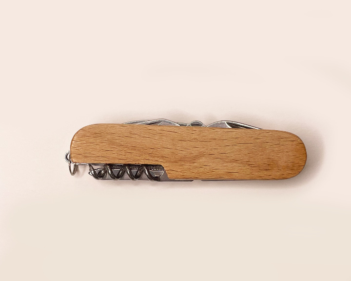 Wooden multi-tool with corkscrew on a beige background