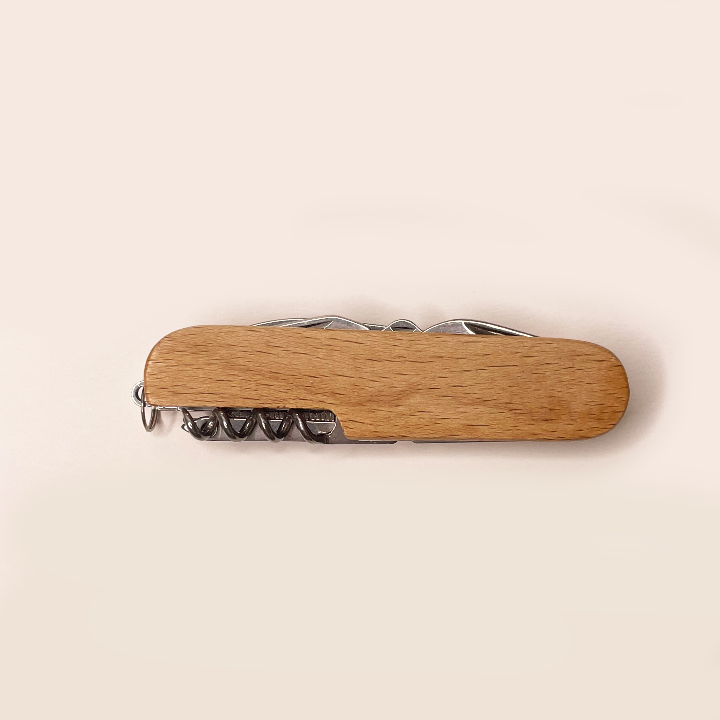 Wooden multi-tool with corkscrew on a beige background