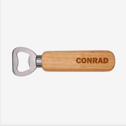 Wooden bottle opener with 'CONRAD' engraving on a white background