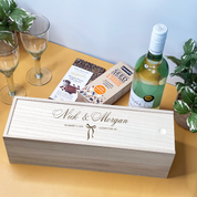Personalized wooden Wedding Wine box with a bottle of wine on a table with glasses and plants.