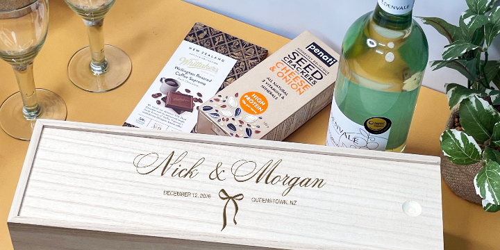 Personalized wooden Wedding Wine box with a bottle of wine on a table with glasses and plants.