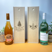 Two wooden christmas wine boxes with engraved designs next to two bottles of Eden Orchards juice and Edenvale wine.