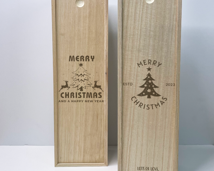 Two wooden wine boxes with Christmas designs and text on a light gray background