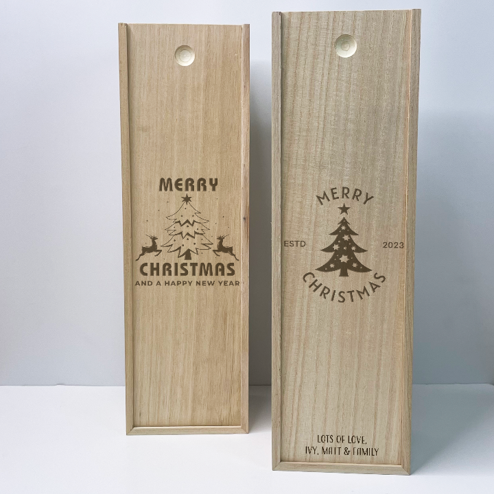 Two wooden wine boxes with Christmas designs and text on a light gray background